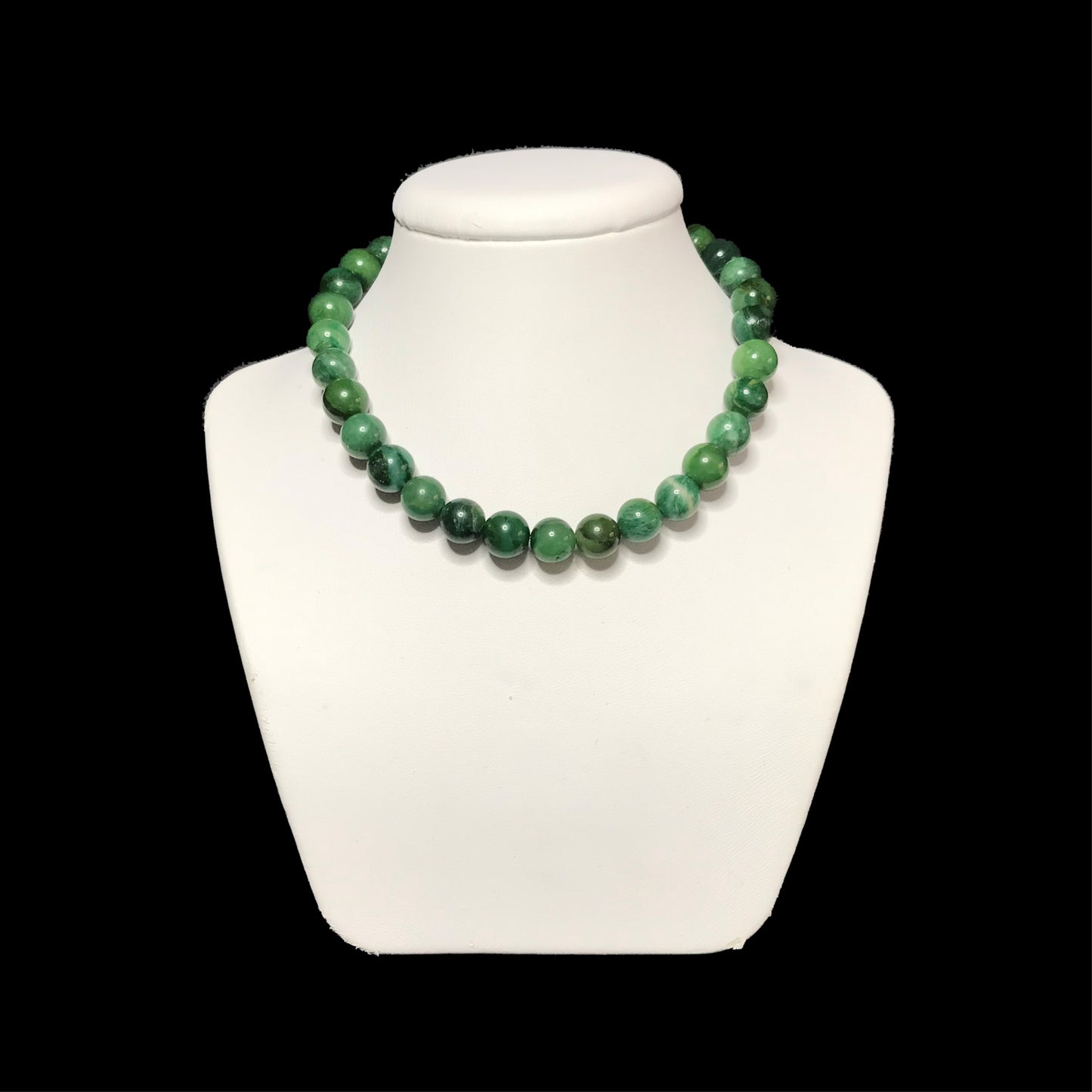 Green gemstone necklace on a white stand