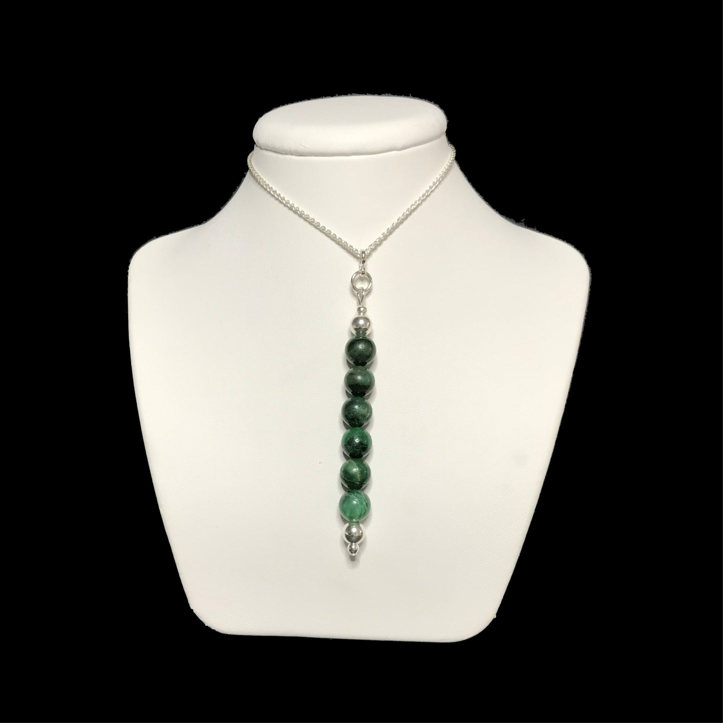 Dark green gemstone pendant on a white stand