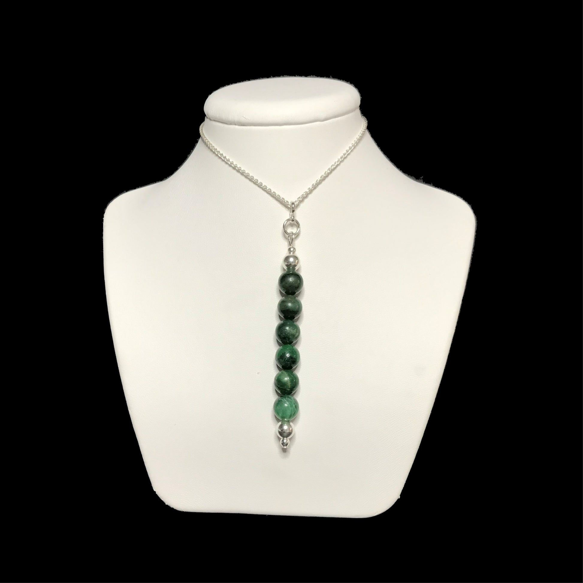 Dark green gemstone pendant on a white stand