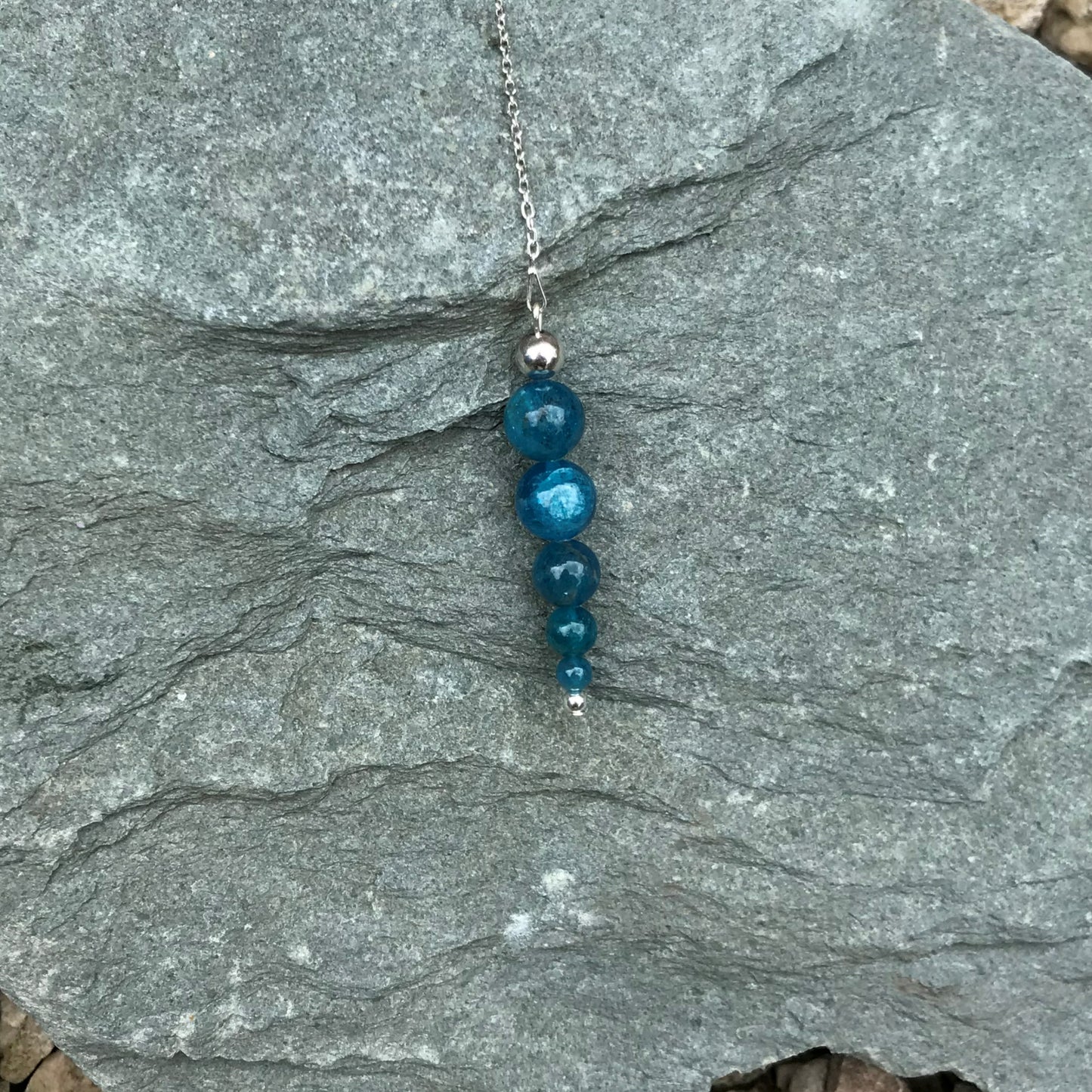 Blue crystal dowsing pendulum on stone