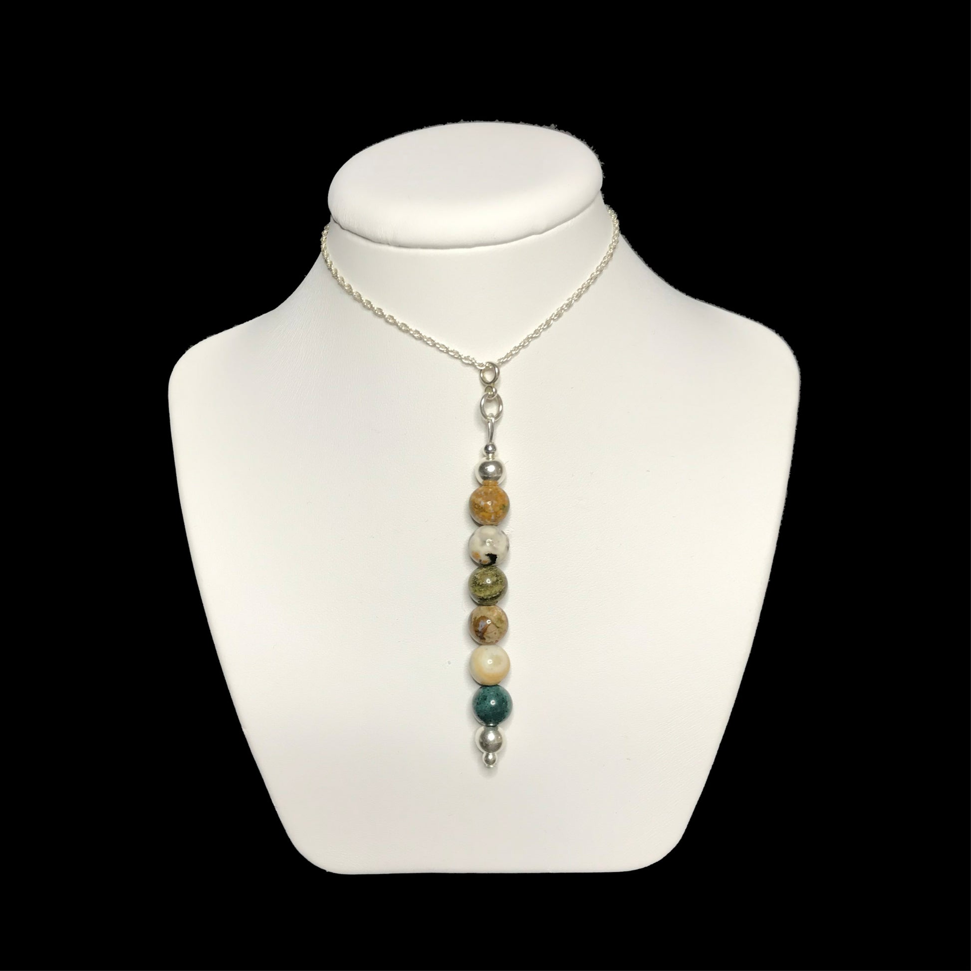 Ocean jasper pendant necklace on a white stand