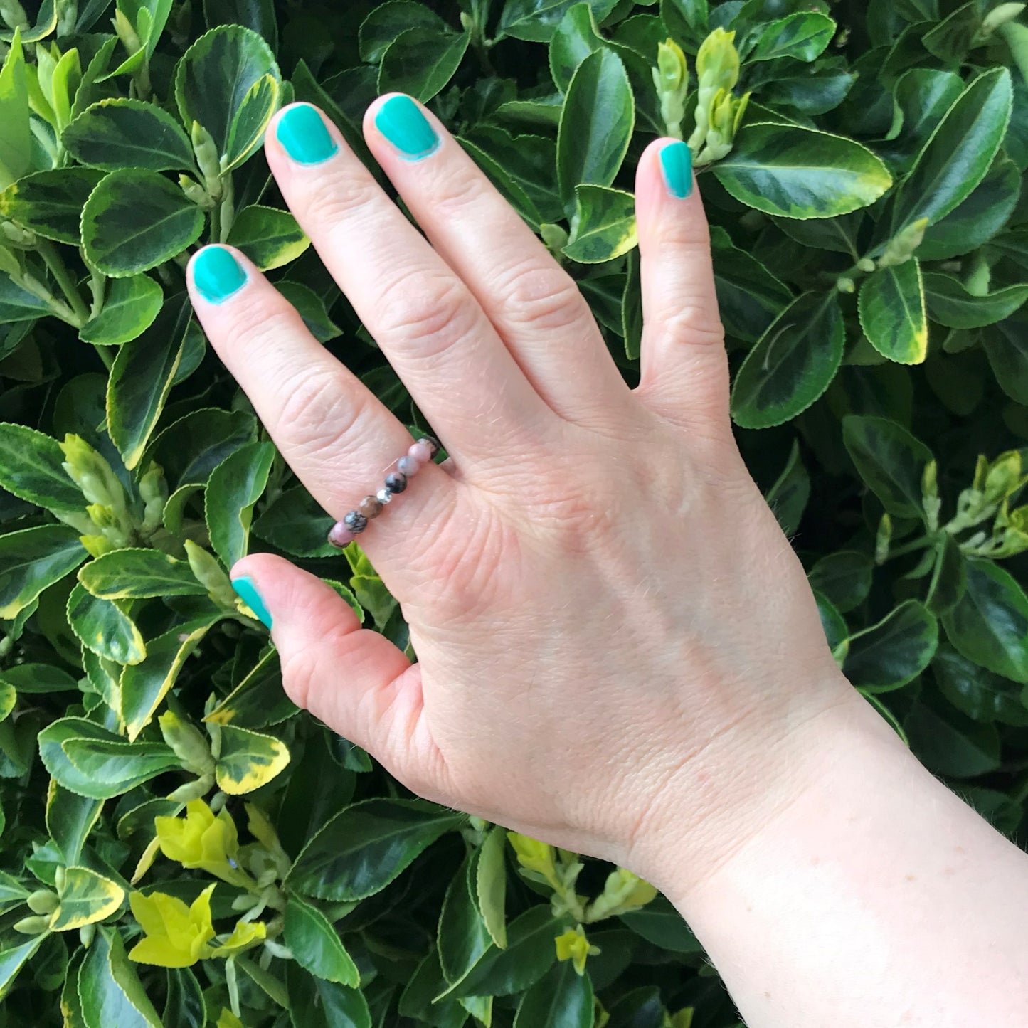 Hand wearing a rhodonite bead stretch ring