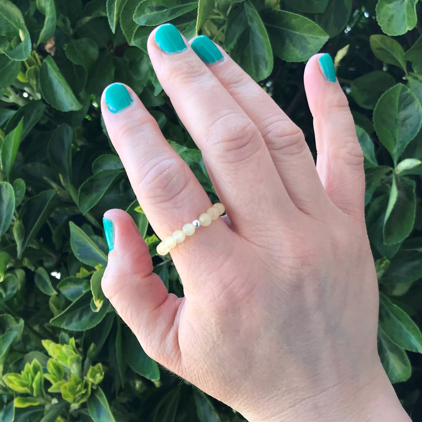 Hand wearing a yellow calcite beaded ring