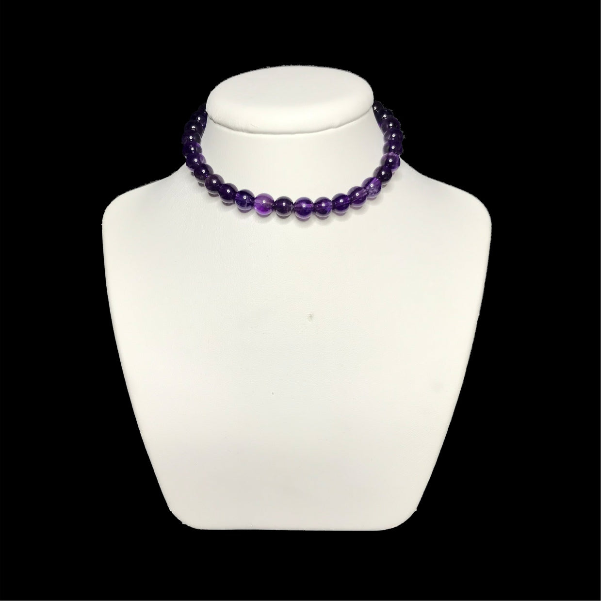 A beaded amethyst handmade choker on a white stand.