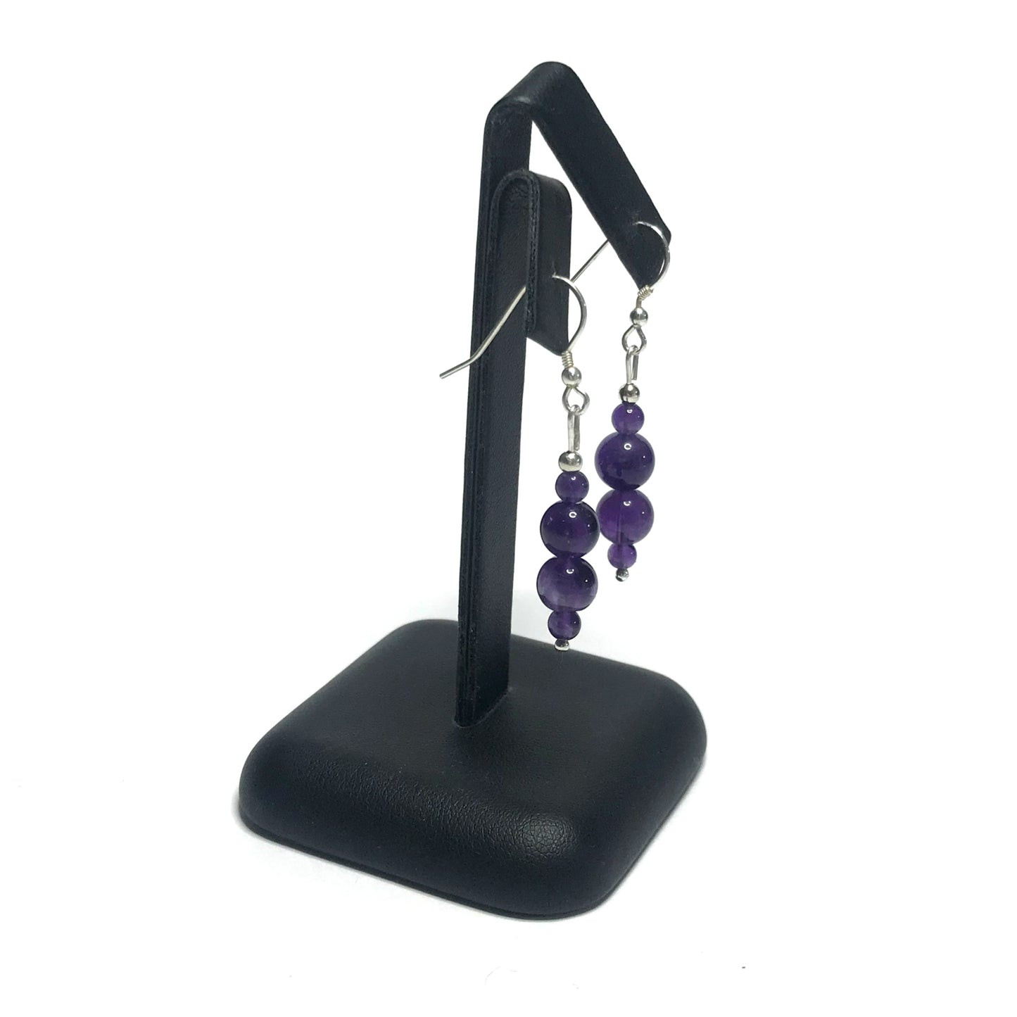Handmade amethyst bead earrings on a black stand.