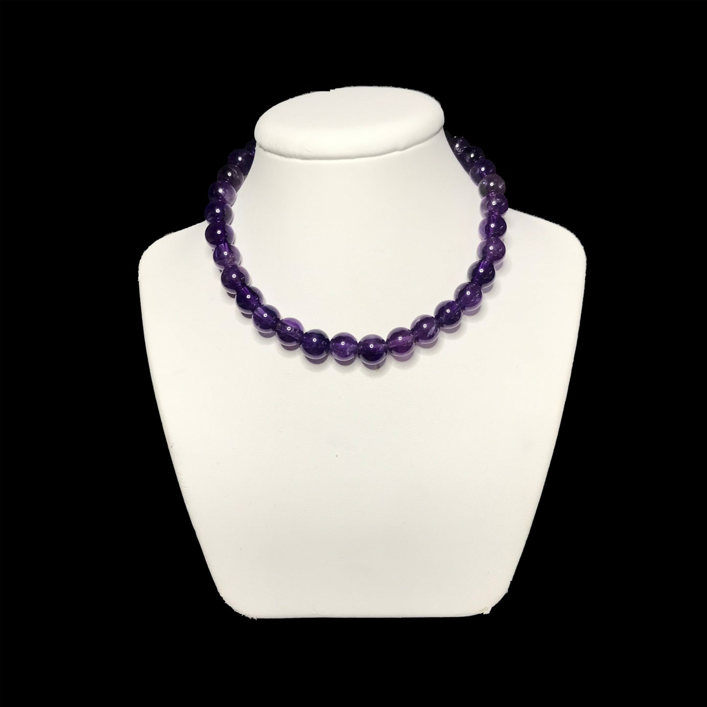 A beaded amethyst handmade necklace on a white stand.