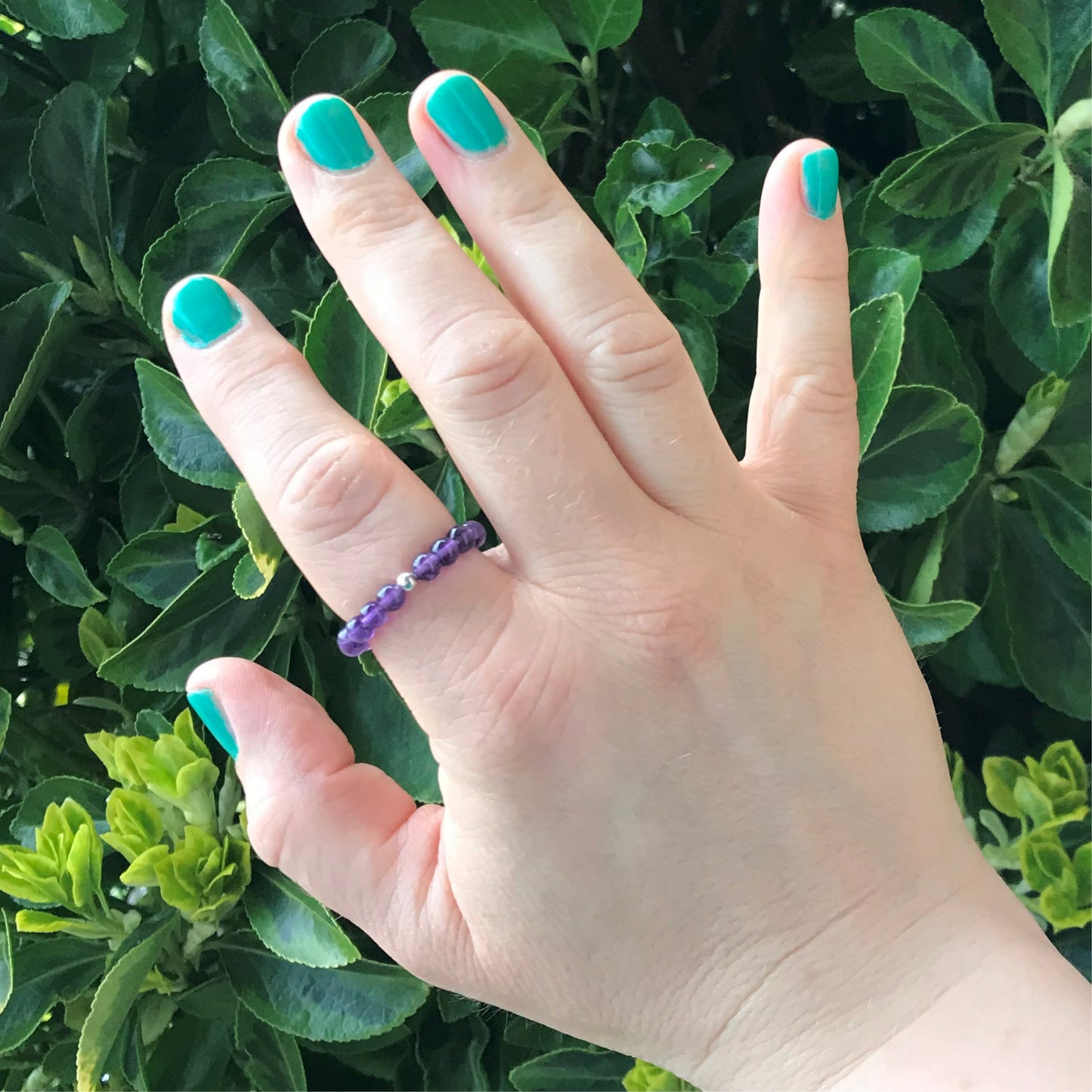 A hand wearing an amethyst ring.