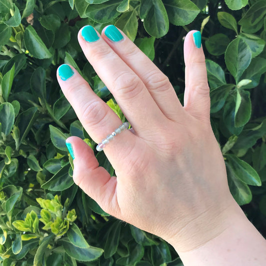 Hand wearing a beaded rainbow fluorite  crystal stretch ring