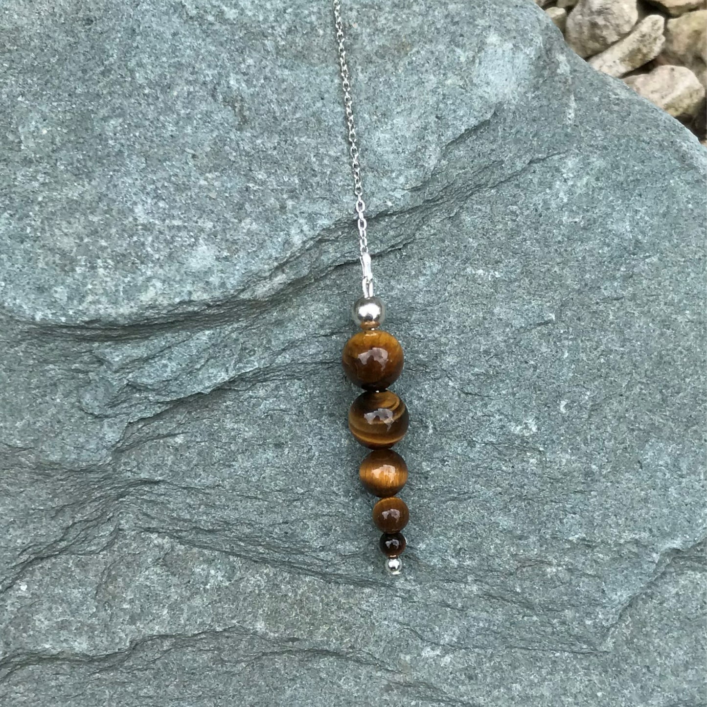 Tiger eye crystal pendulum on stone