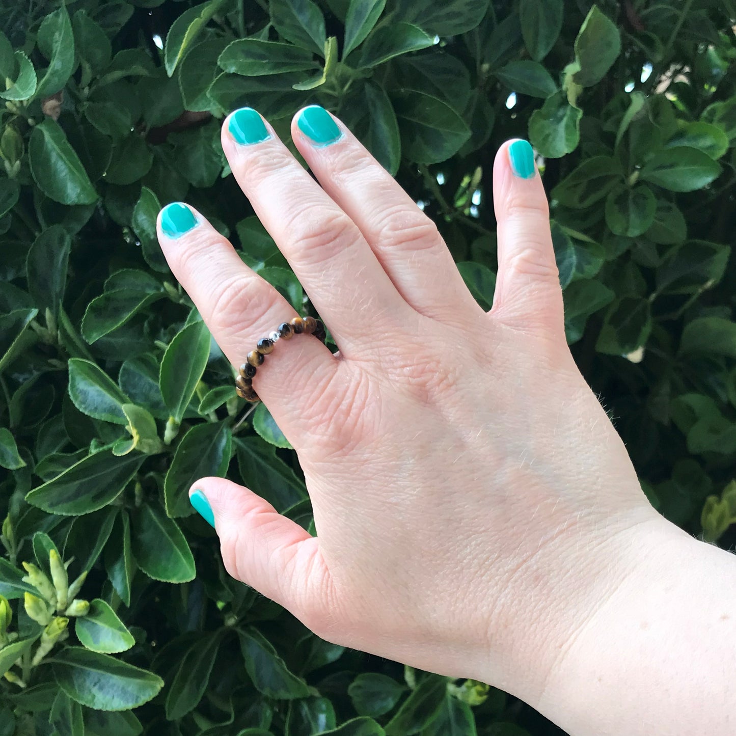 Hand wearing tiger's eye crystal bead ring